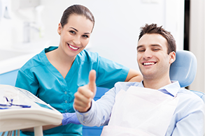 Man with straight teeth in dental chair giving thumbs up