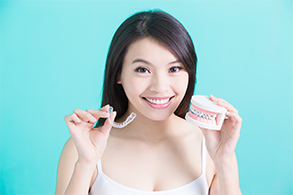 Woman holding Invisalign aligner and model smile with braces