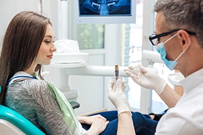 Dentist showing patient dental implant model