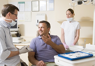 Man in dental chair talking to dentist